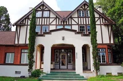 Front view of a Tudor-style house with white stucco, dark wood trim, and green steps.
