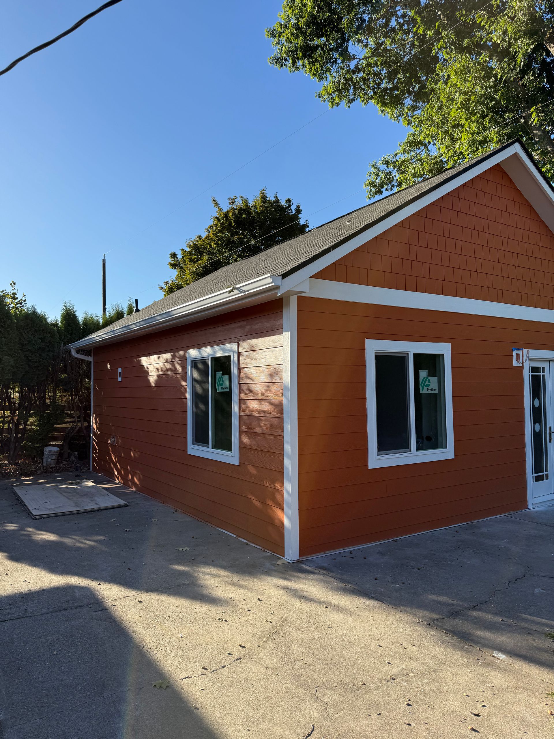 Small orange building with white trim, two windows, and dark roof under a clear blue sky.