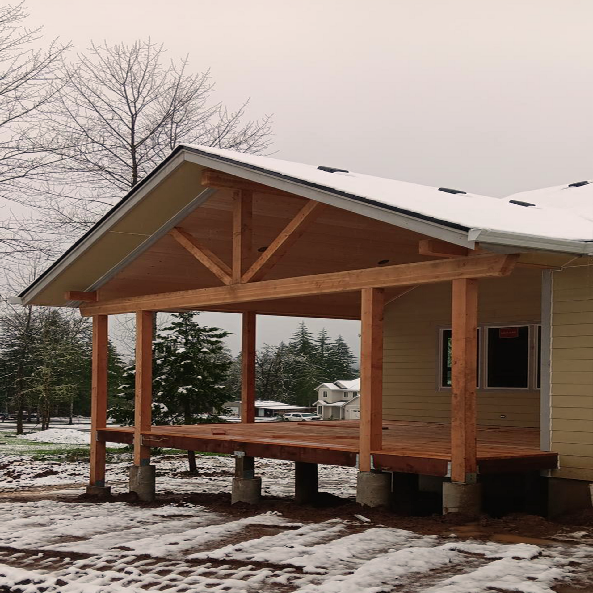 Covered porch with wood frame and snow on the ground.