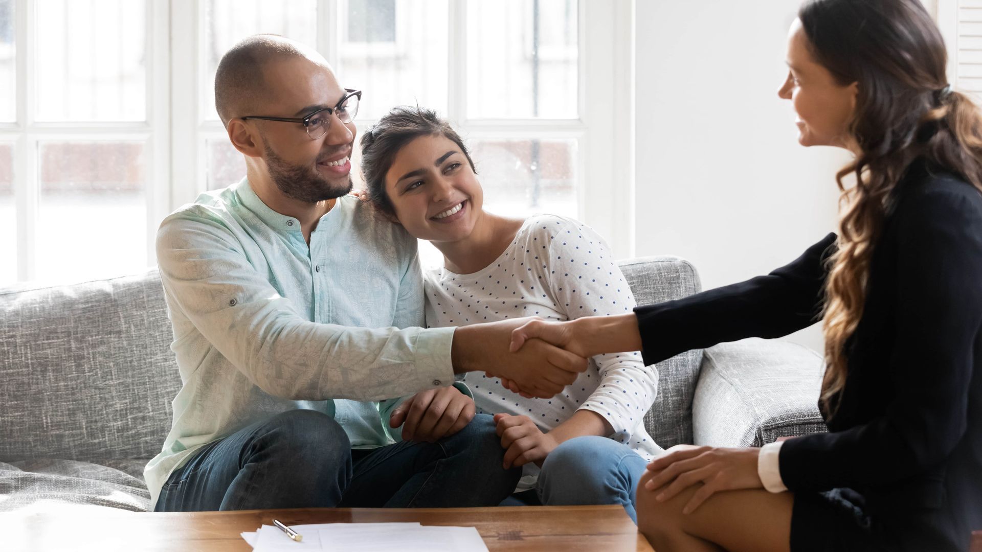 A couple shaking hands with a professional seated across from them.