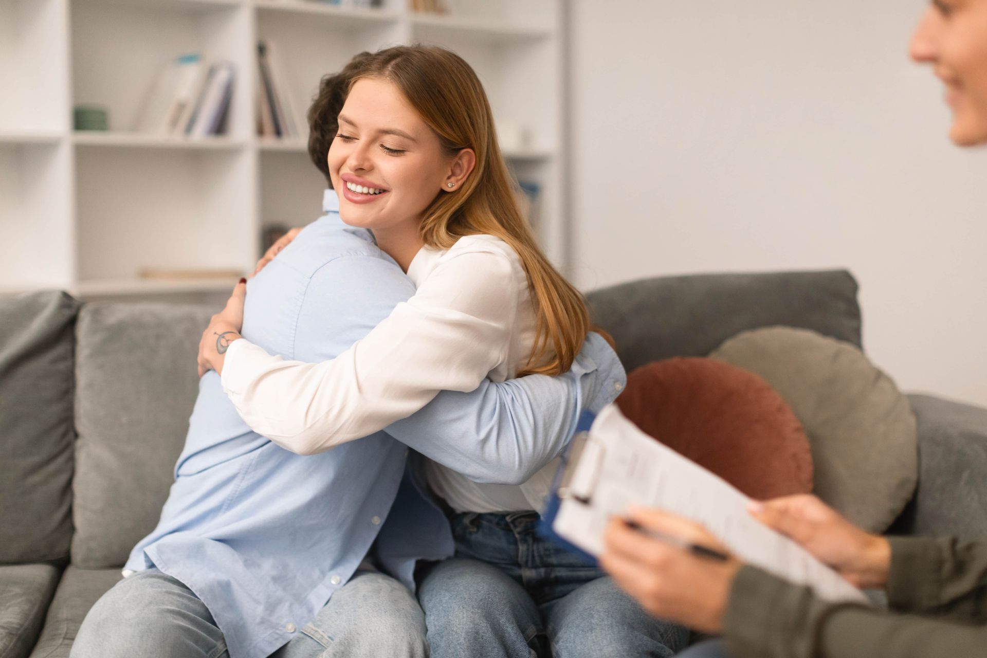 Couple hugging on a couch in a therapy session, smiling at each other.