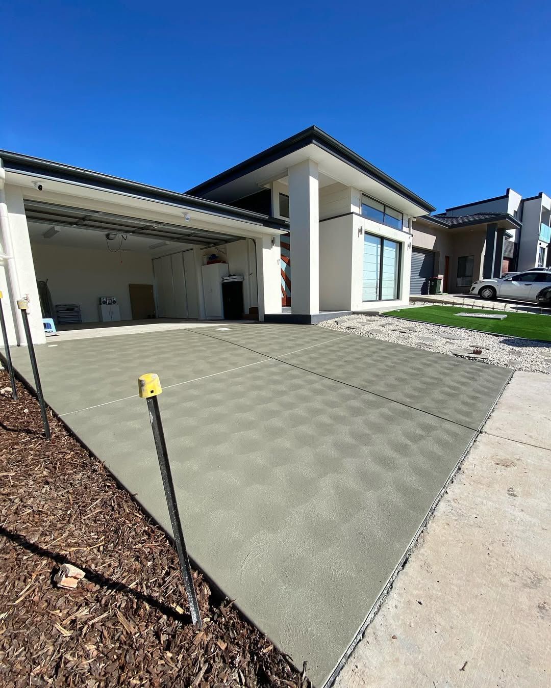 Modern house exterior with large paved patio and clear blue sky