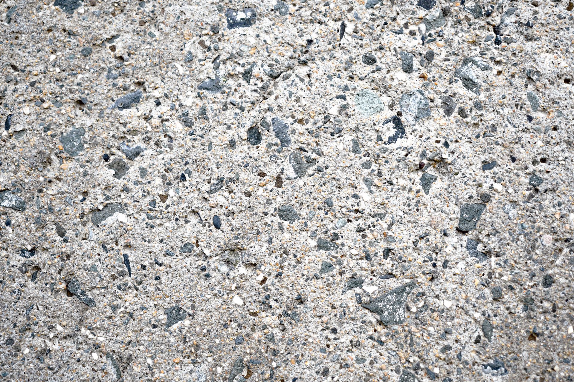 Close-up of rough gray concrete with small pebbles and speckled texture