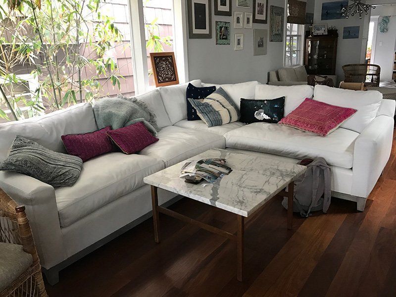 White sectional sofa with colorful pillows and a marble coffee table in a living room.