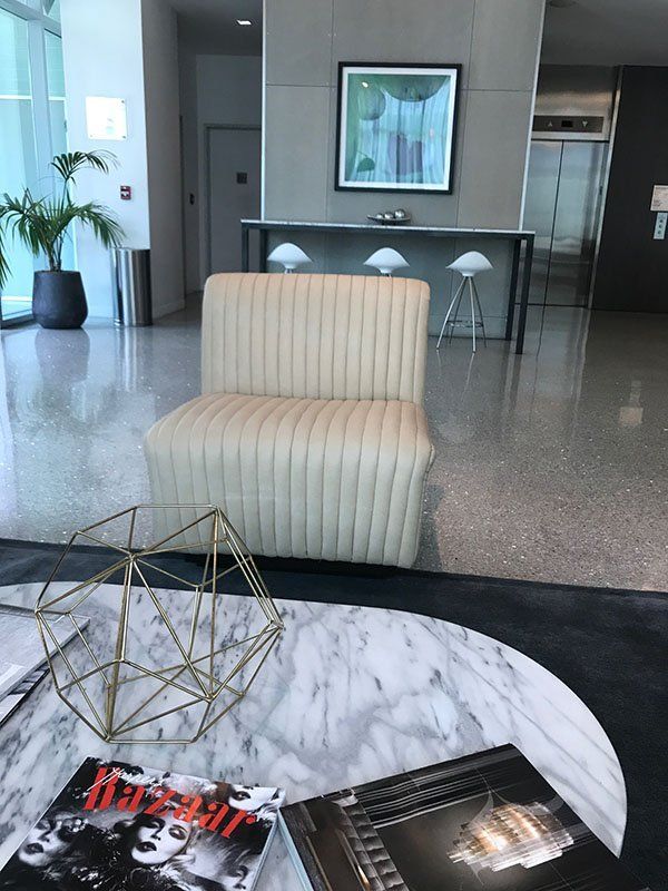 Lobby with cream-colored chair, marble coffee table with books, artwork, and bar seating.