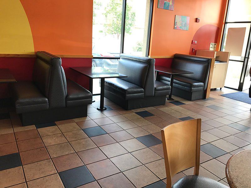Restaurant interior with booths, tables, and tiled floor; orange and yellow walls.