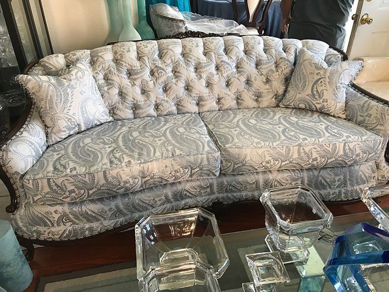 Tufted light blue paisley sofa with two matching pillows.