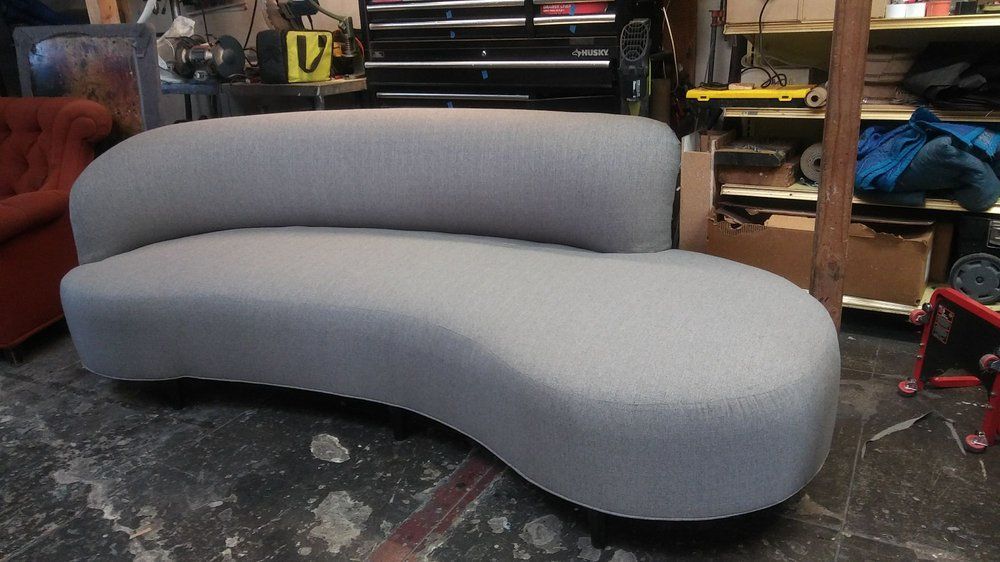 Gray, curved sofa in a workshop setting.