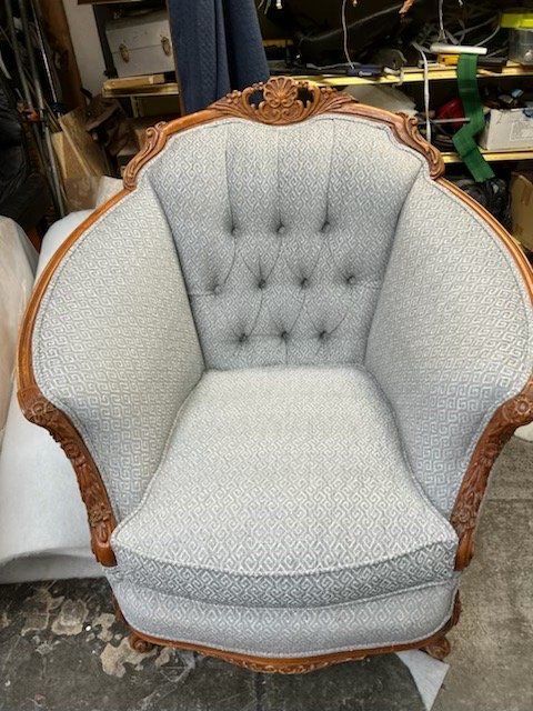 Tufted armchair with light gray patterned upholstery and ornate wooden frame.