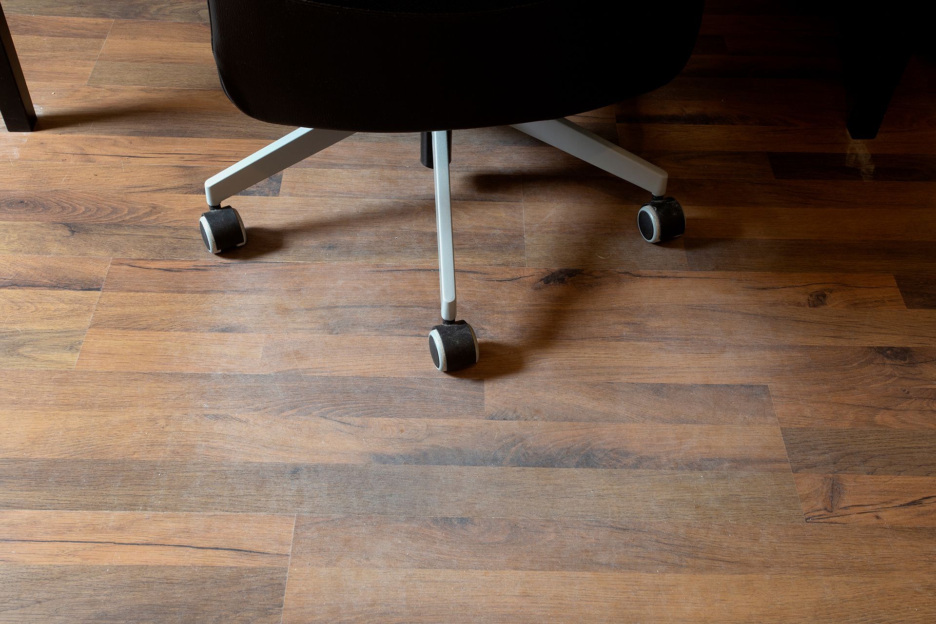 A close up of a chair with wheels on a wooden floor.