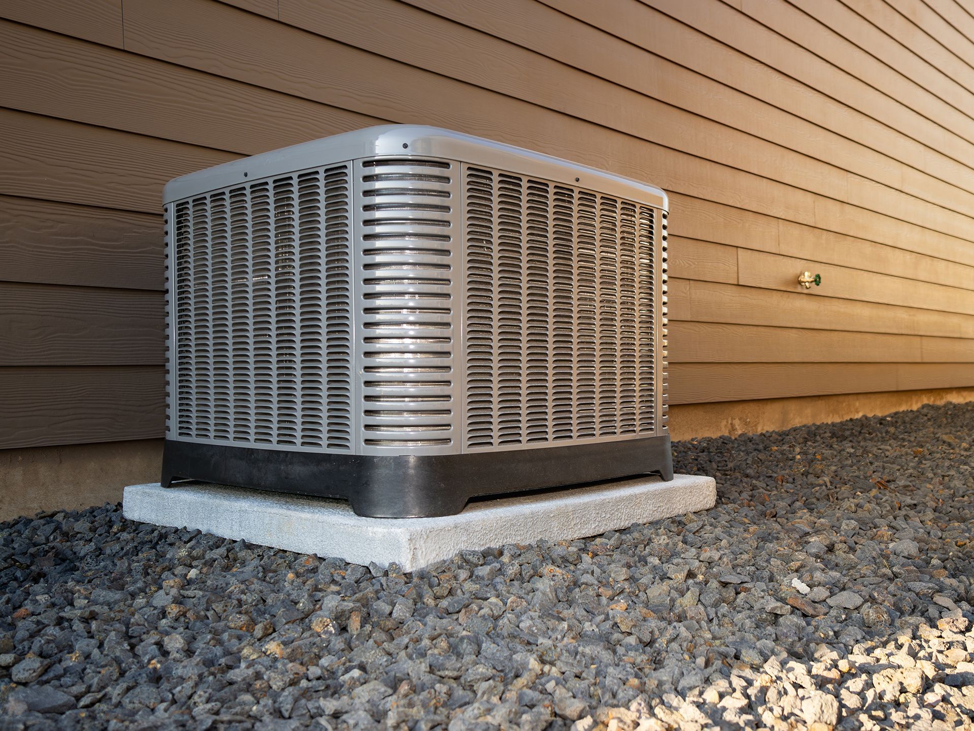 An air conditioner is sitting on the side of a house.