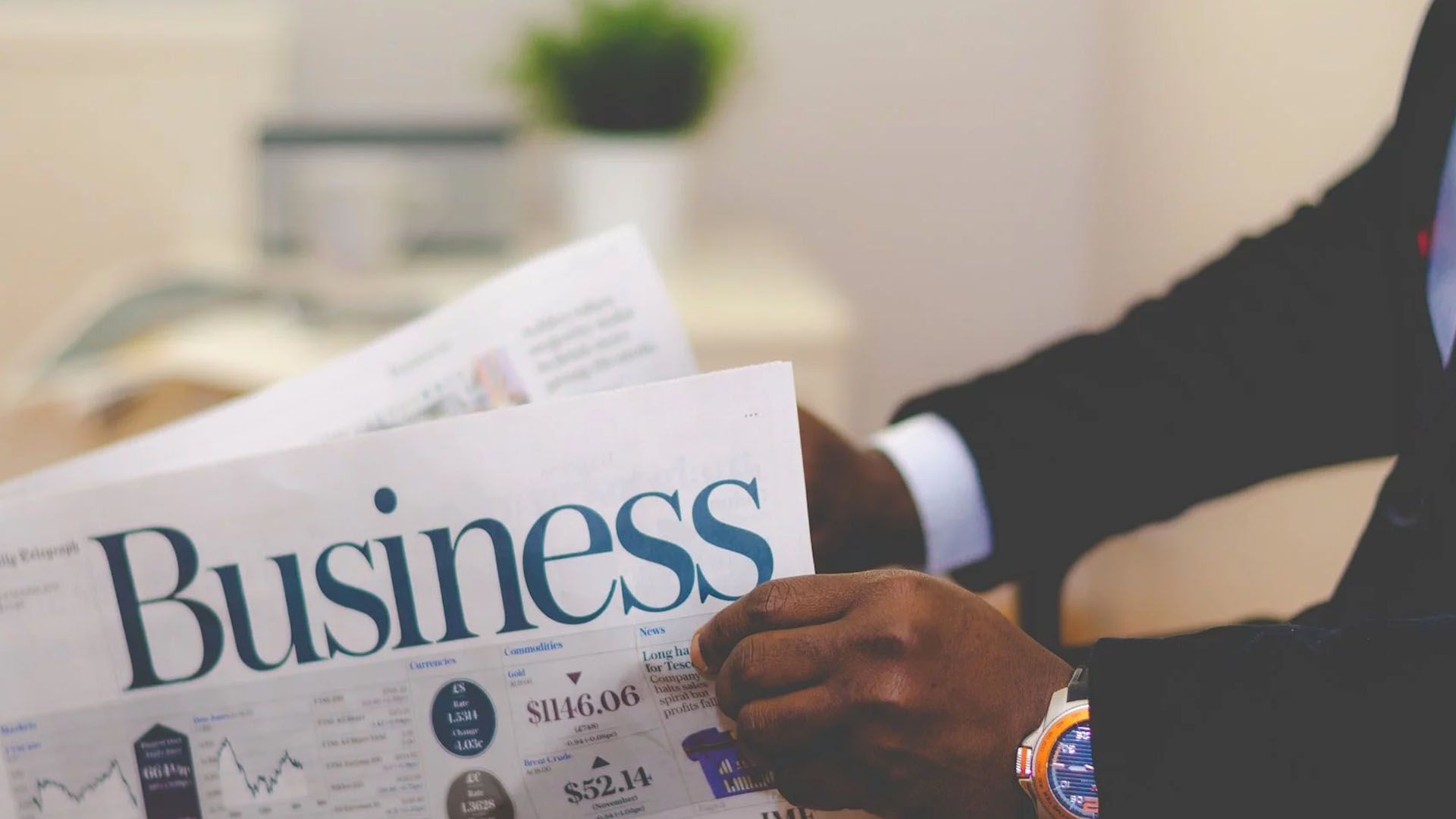 Une personne en costume tenant un journal dont le titre est « Affaires ».