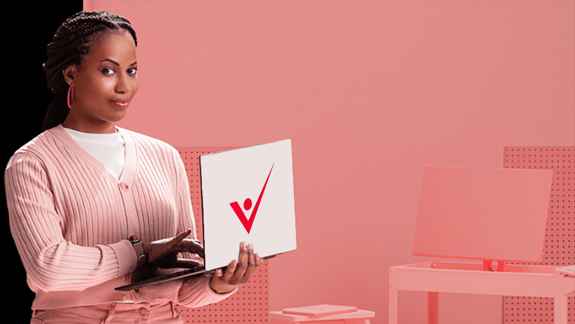 Femme tenant un ordinateur portable et une feuille de papier avec un logo à coche rouge dans une pièce rose.