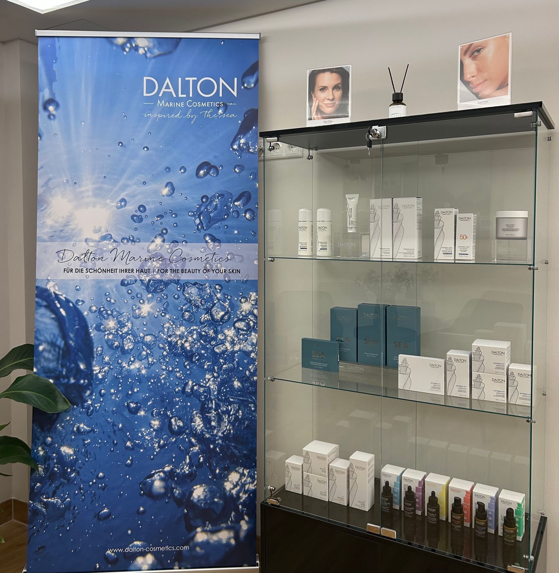 Glass display cabinet with skincare product boxes and bottles on shelves in a clinic or salon.