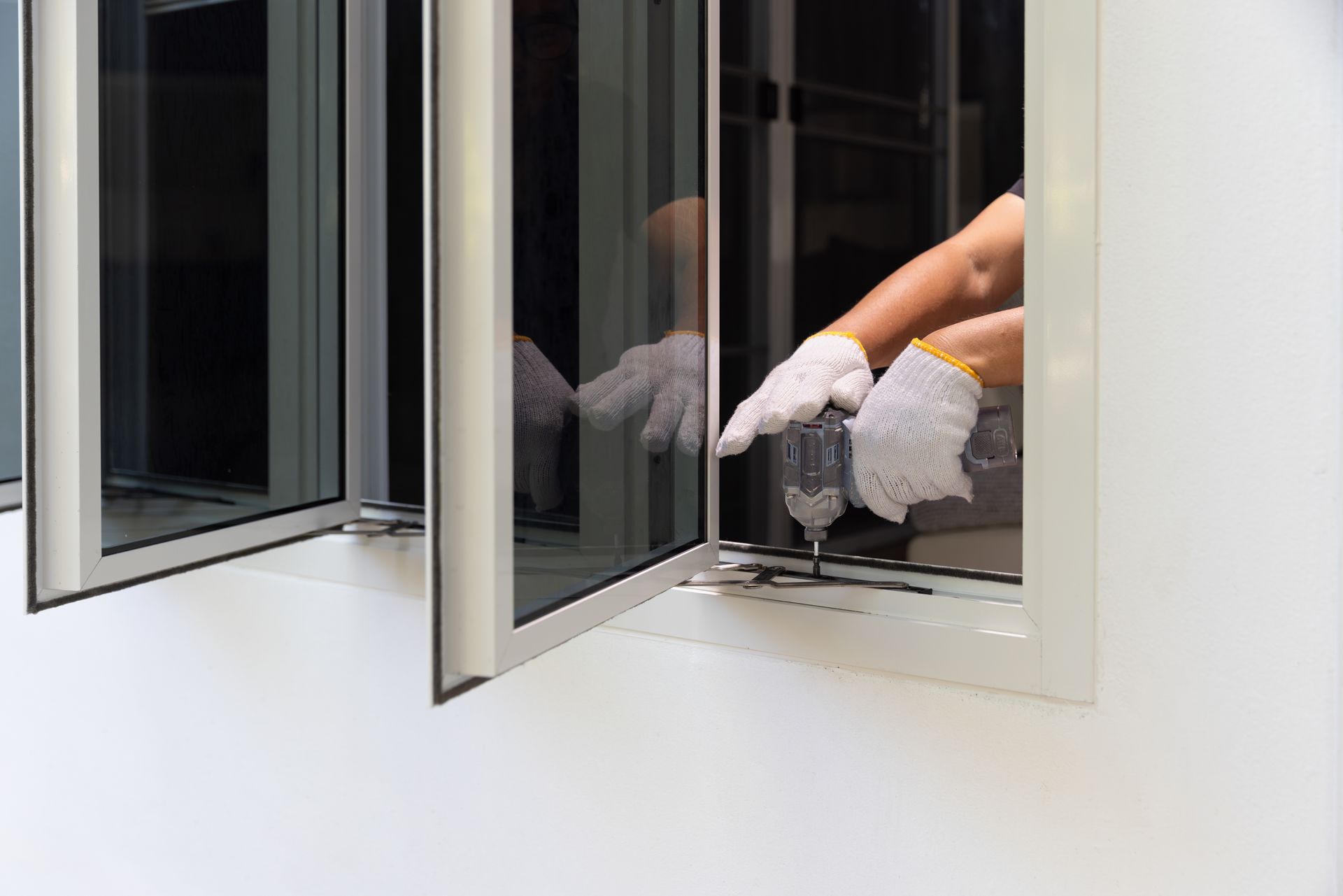Person in white gloves cleaning a window from the inside of a building