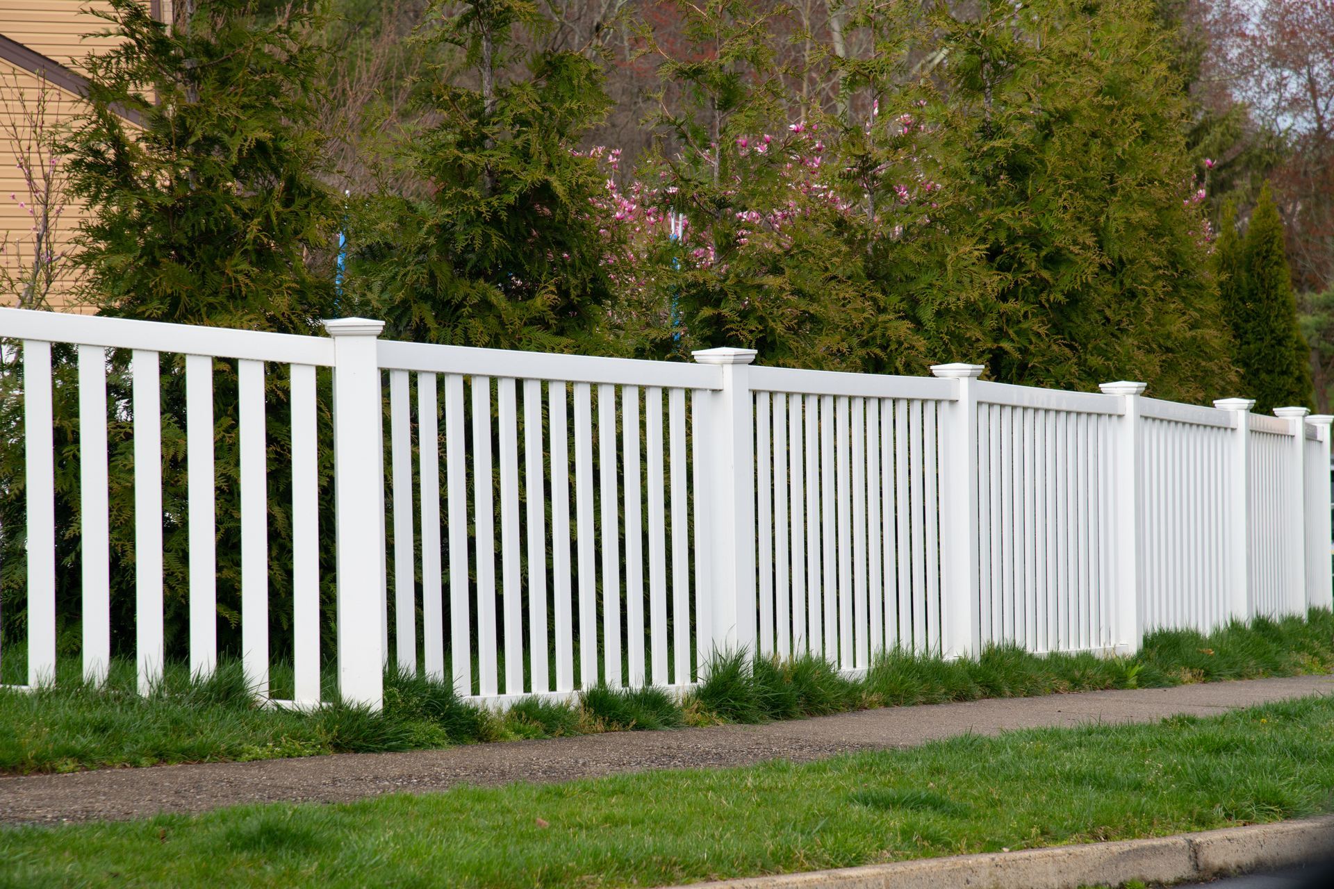 A concrete fence along a sidewalk with a tree in the background.
