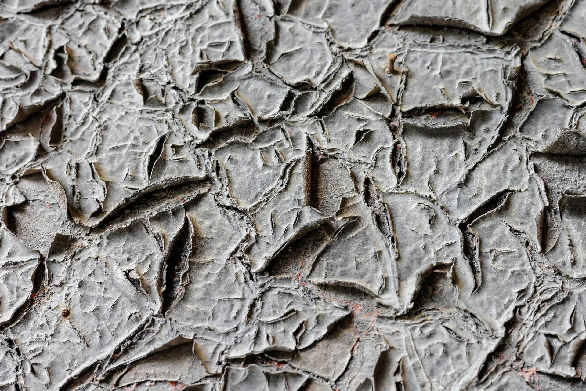 Cracked gray paint, with a textured, peeling surface.