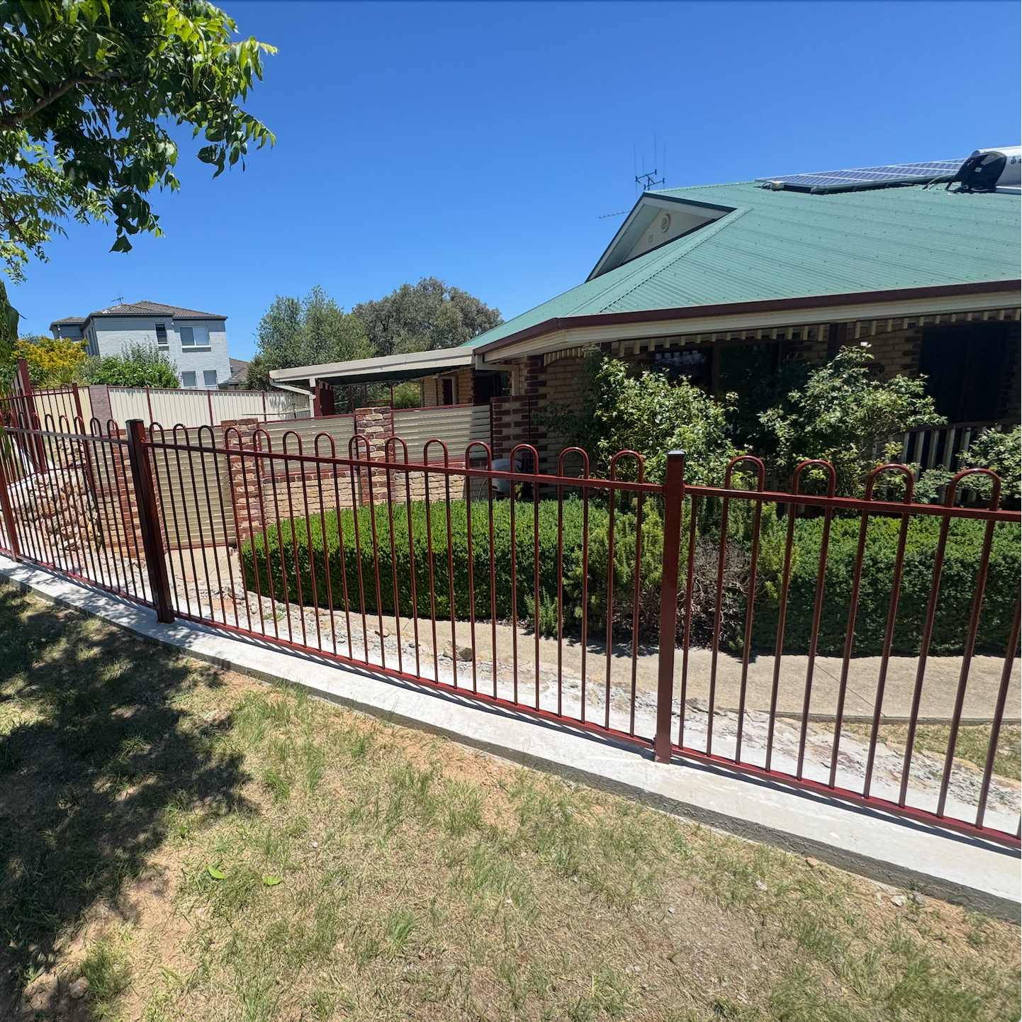A black wrought iron fence surrounds a brick pillar