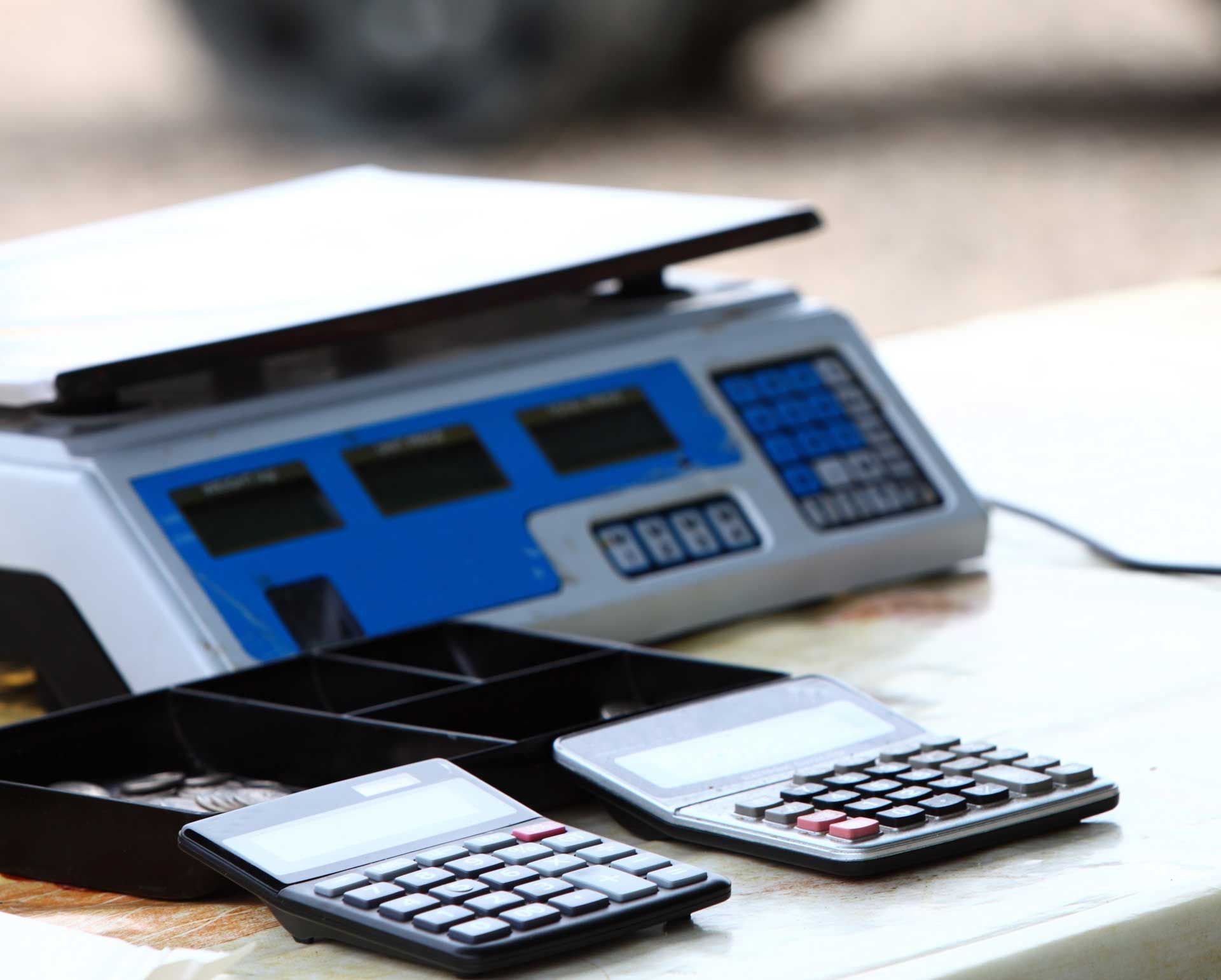 Two calculators are sitting on a table next to a scale