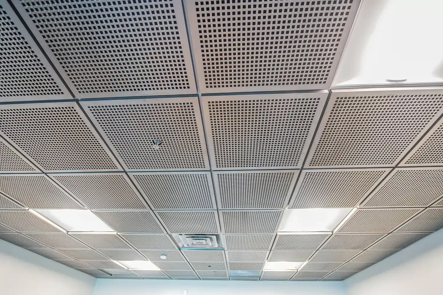 Perforated metal ceiling tiles with recessed lighting.
