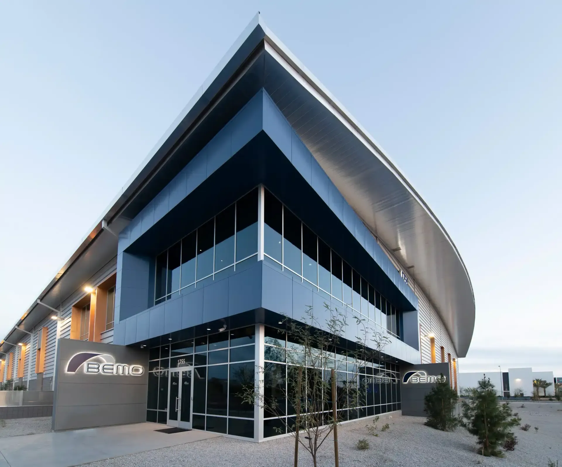 Modern blue and gray building with large windows and a curved roof,