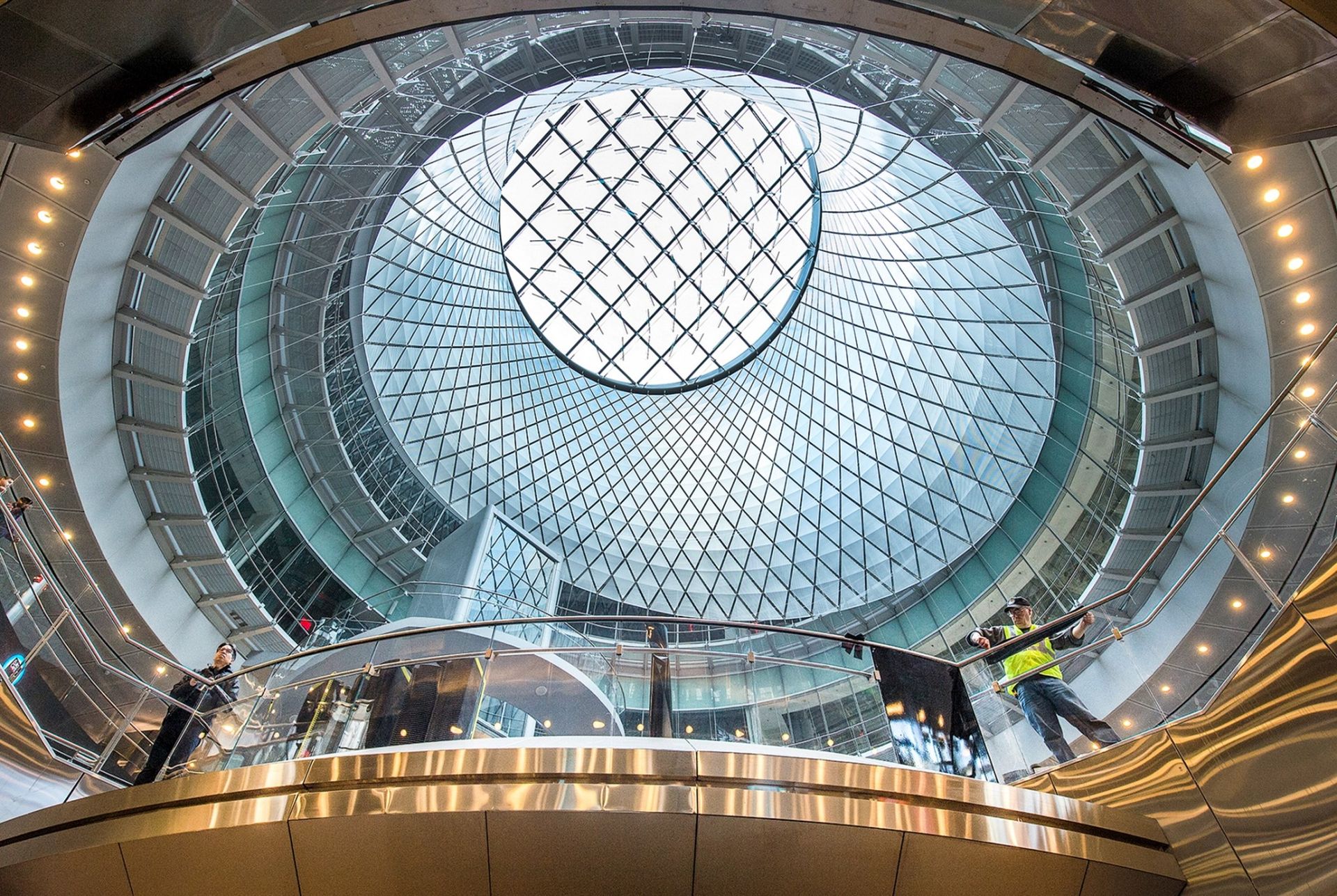 Interior view of a modern building with a circular glass dome and a worker.