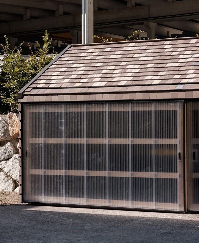 Wooden shed with a cedar shingle roof and a transparent corrugated panel door.