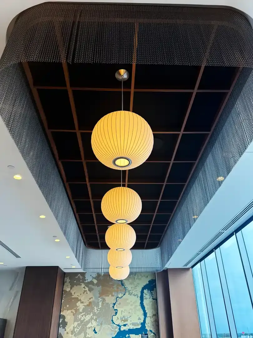 Four glowing spherical pendant lights hang from a patterned ceiling; view angled upwards.