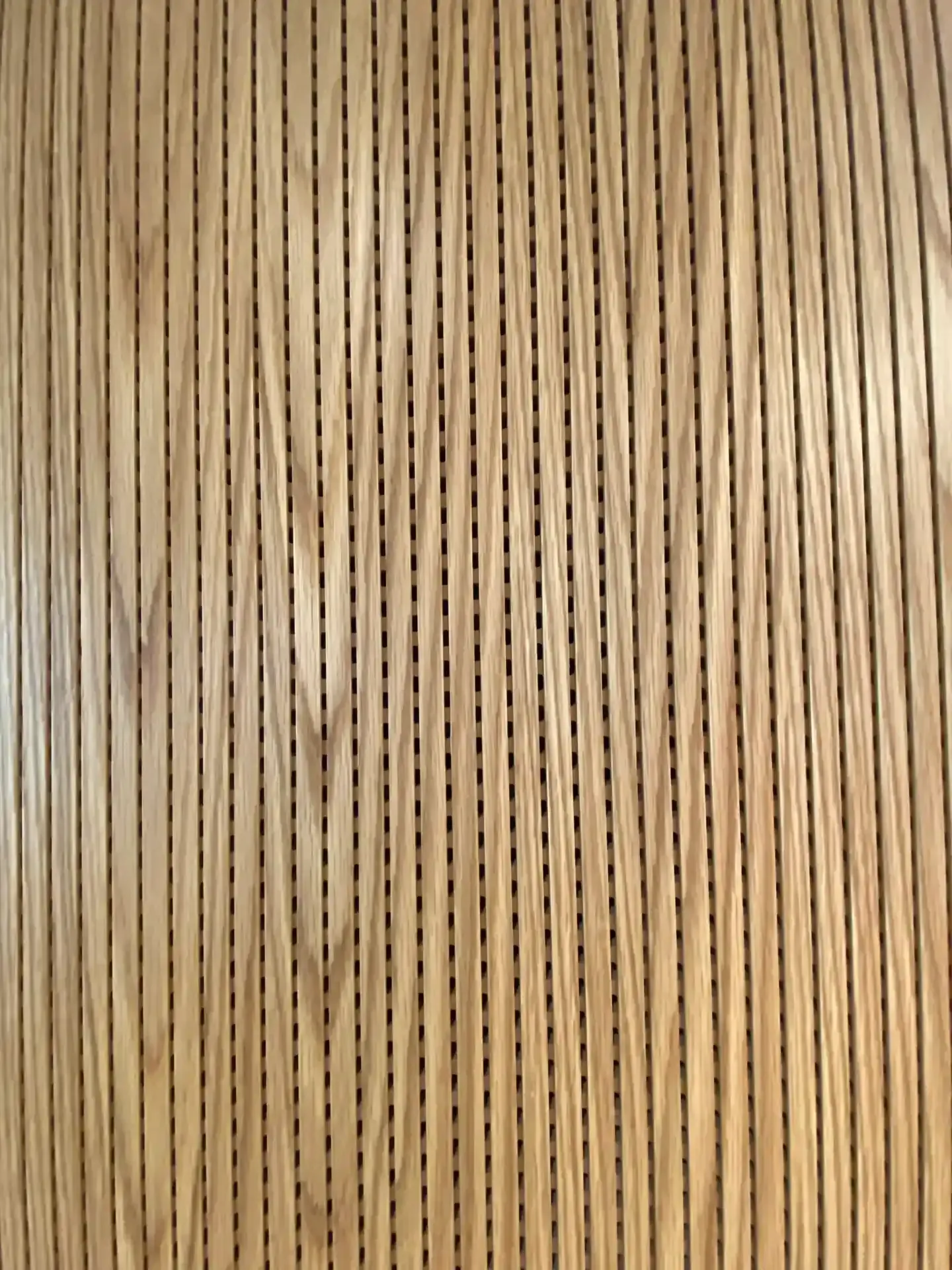 Wood panel with vertical lines and evenly spaced black perforations.