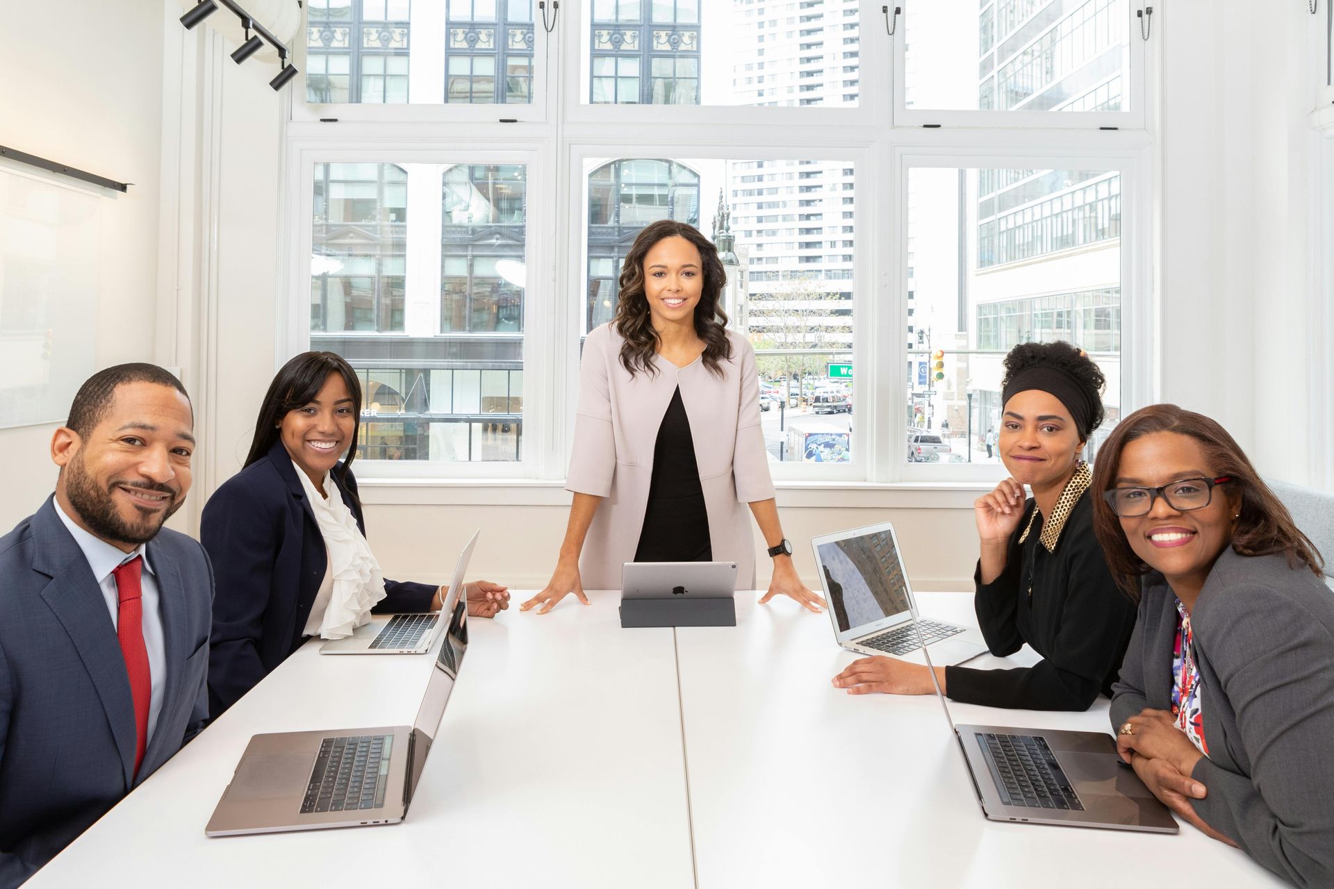 Business team in formal attire at a white table in an office setting.
