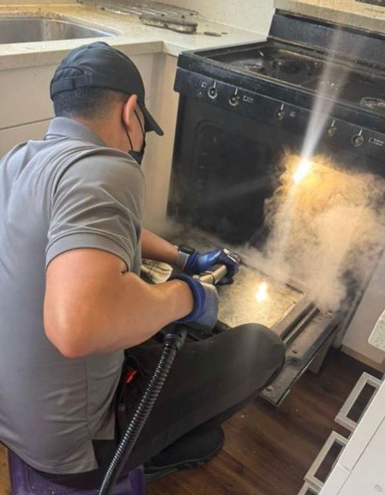 Yellow-gloved hands cleaning a smoky fireplace with a vacuum brush attachment
