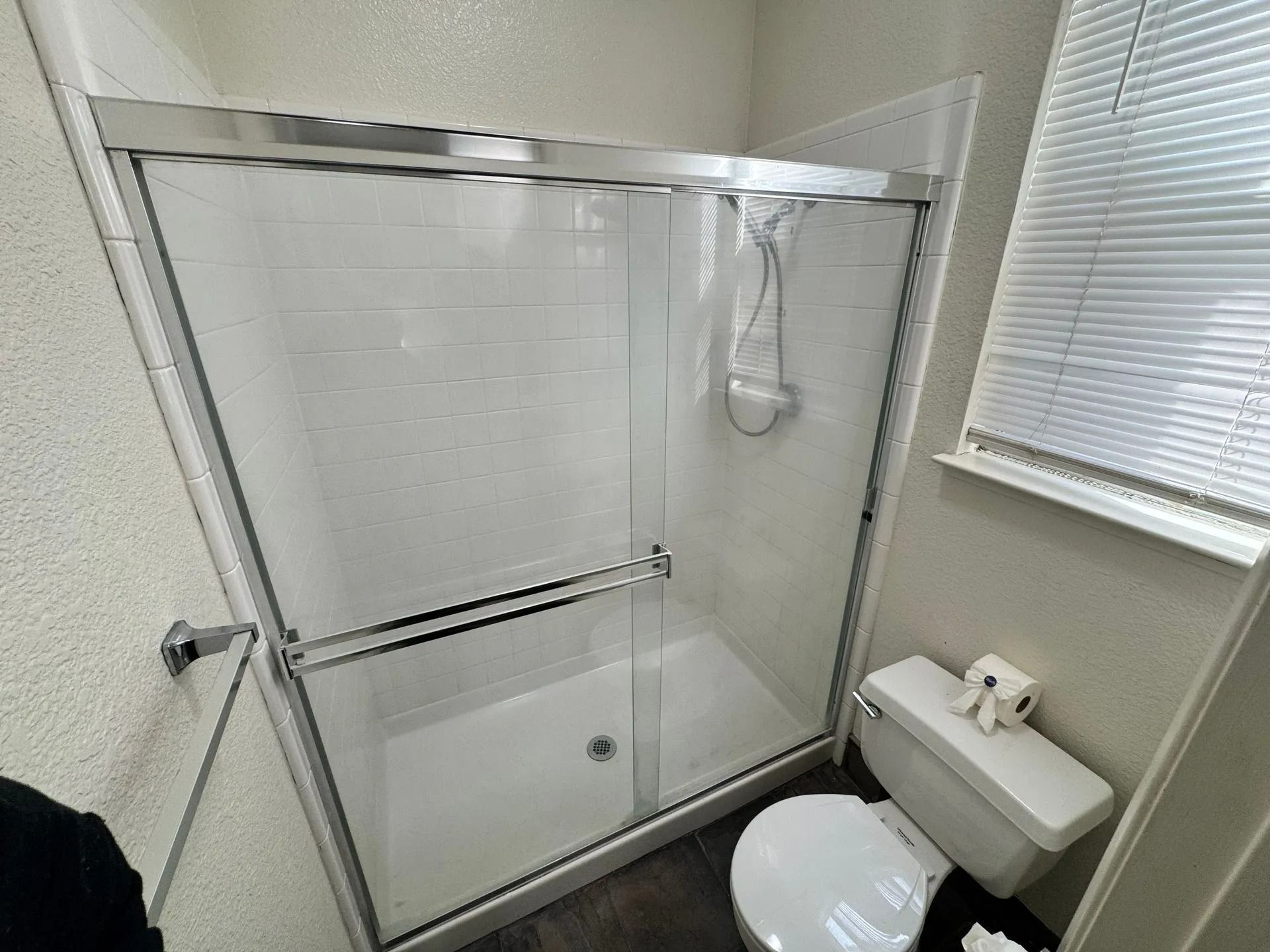 Small bathroom with a glass shower tub, white toilet, and window blinds.
