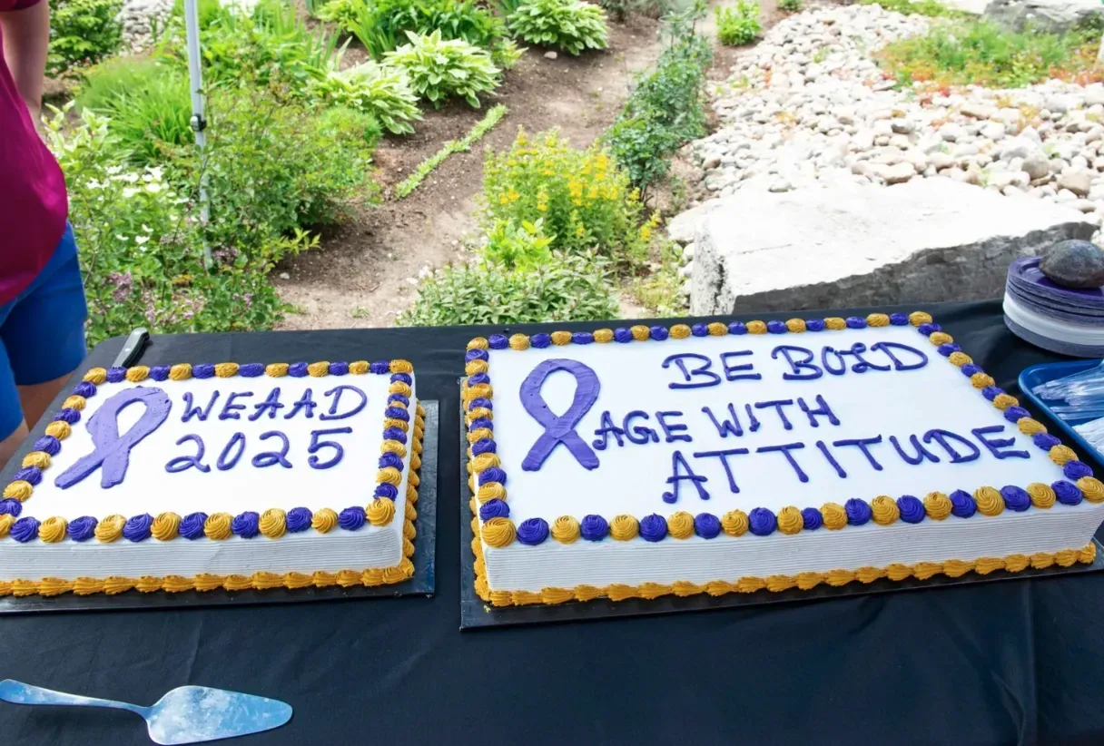 Two decorated cakes with blue ribbon messages at an outdoor event table