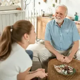 Two people talking in a bright living room, with a bowl on the coffee table.