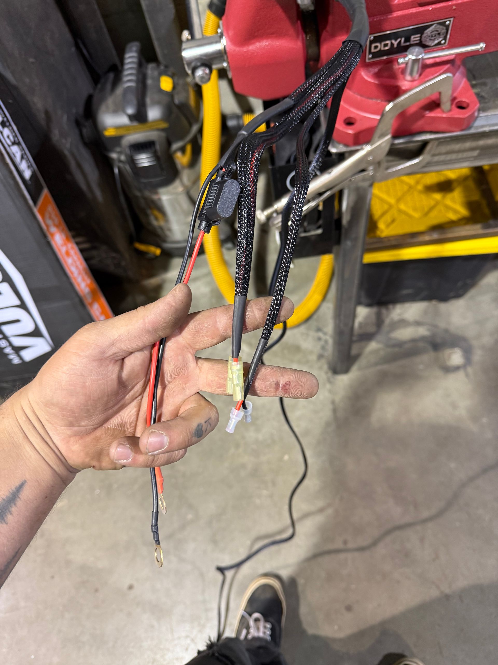 Hand holding a bundle of black wires with red and white wires, likely for an electrical component.