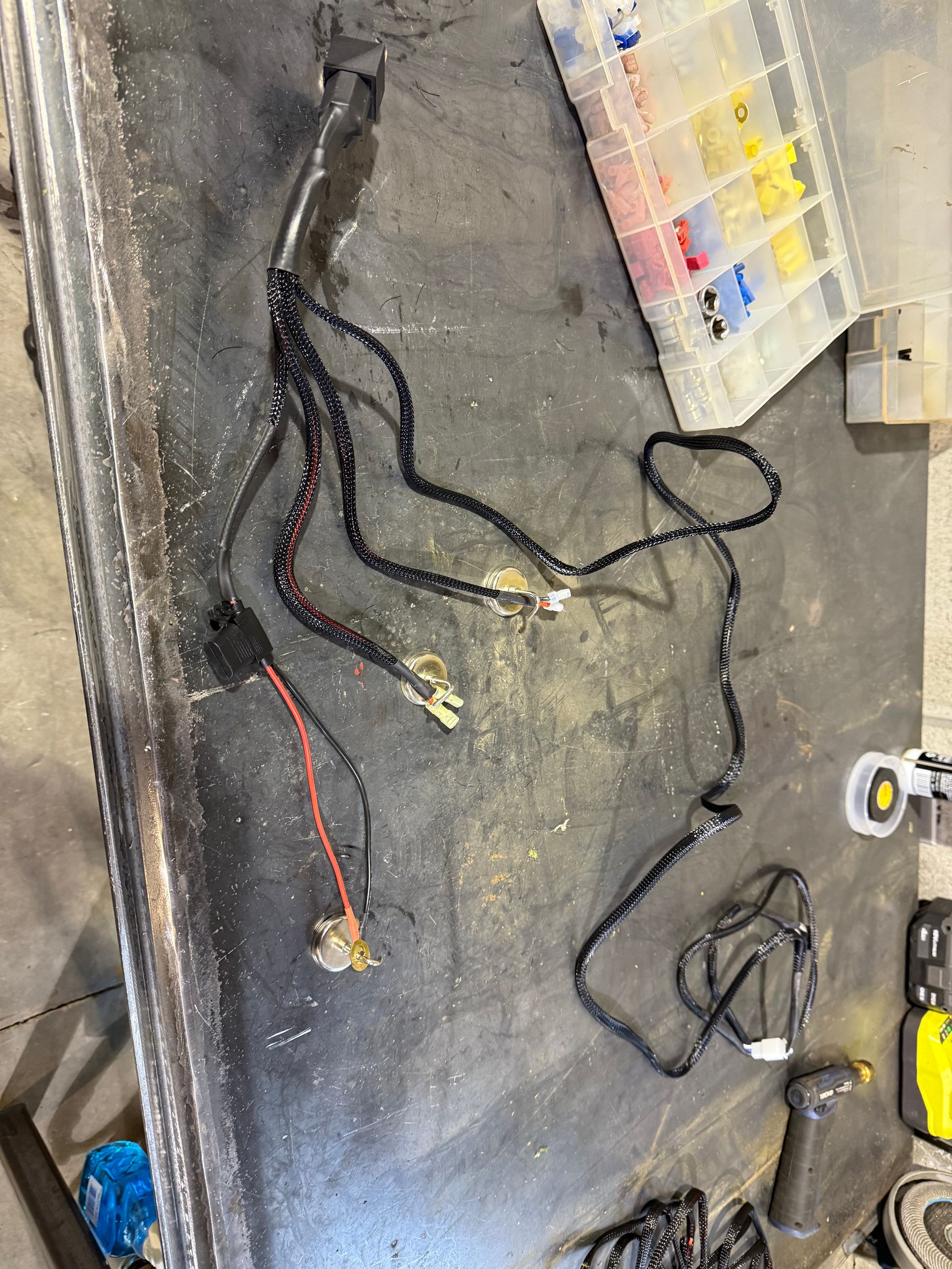 Black electrical wiring harness with connectors on a workbench.