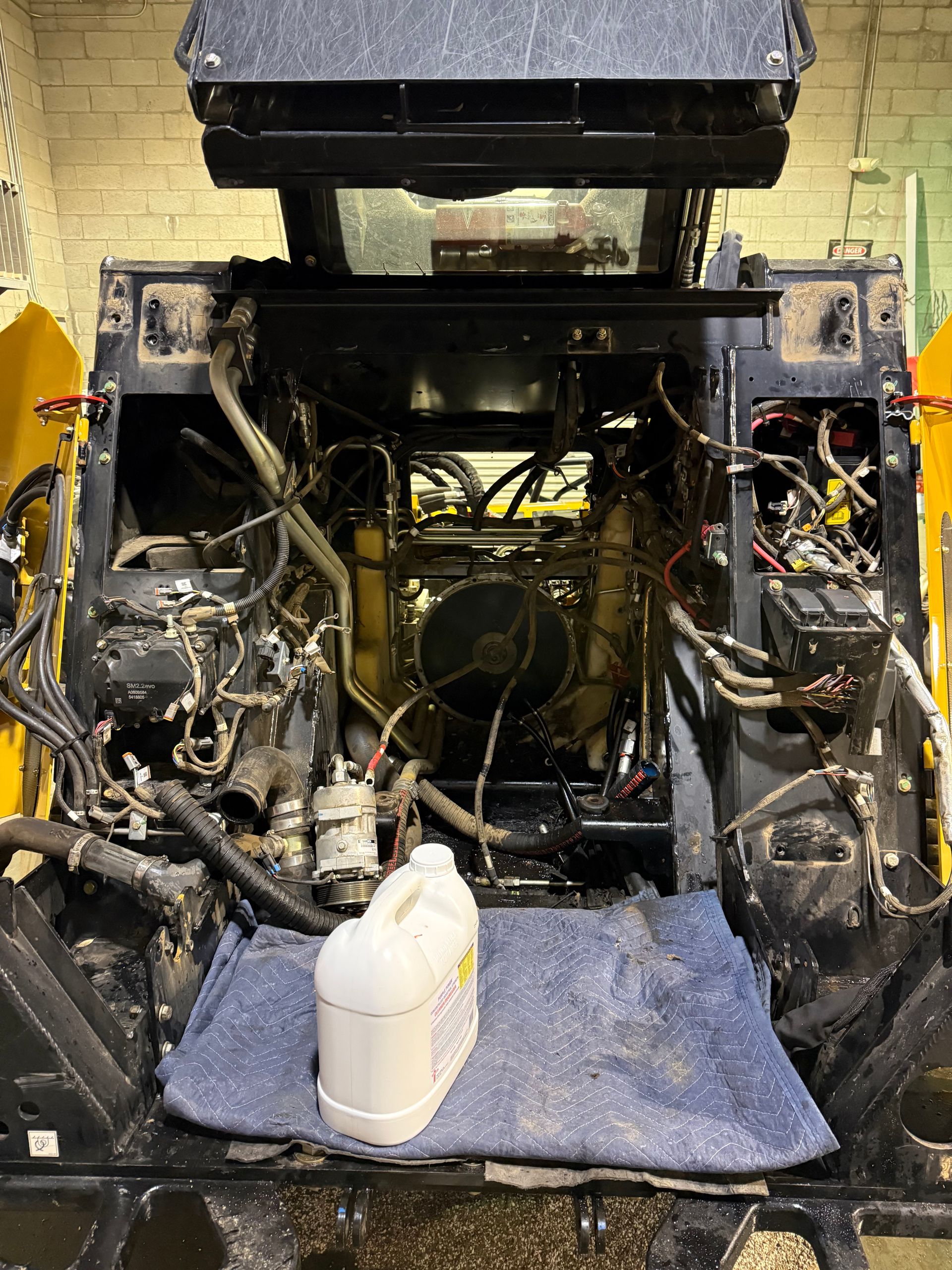 Open engine bay of heavy machinery with oil container.