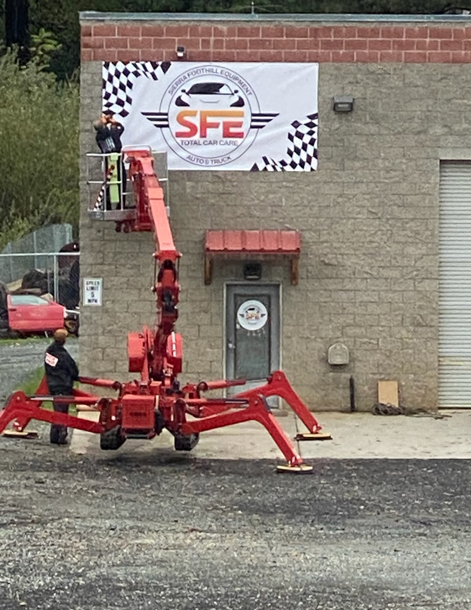 Workers on a red lift installing a banner for 