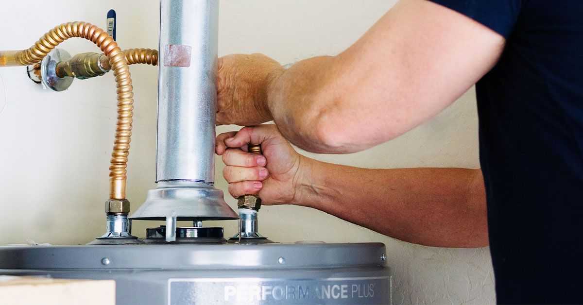 Plumber servicing a residential water heater, checking connections during water heater maintenance o