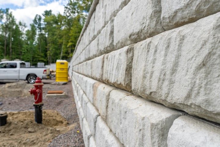 Close-up of a stone retaining wall under construction next to a fire hydrant and a white pickup truck.