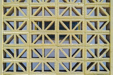 Yellow geometric breeze block wall pattern.