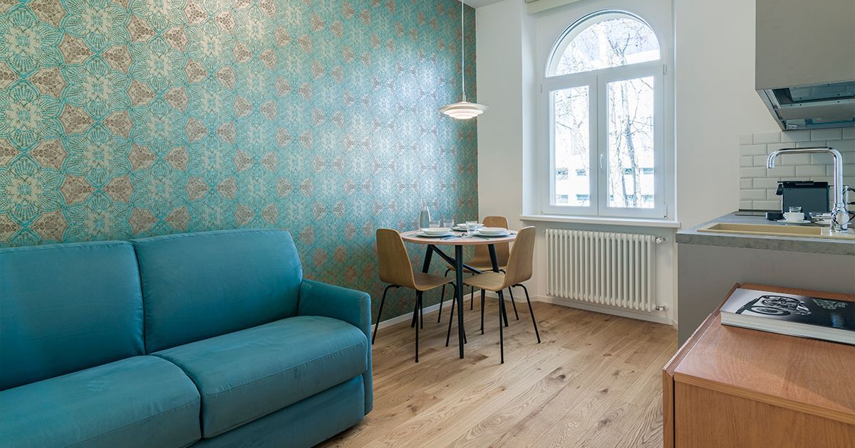 Una camera d'albergo con un letto, due sedie, un tavolo e una finestra.