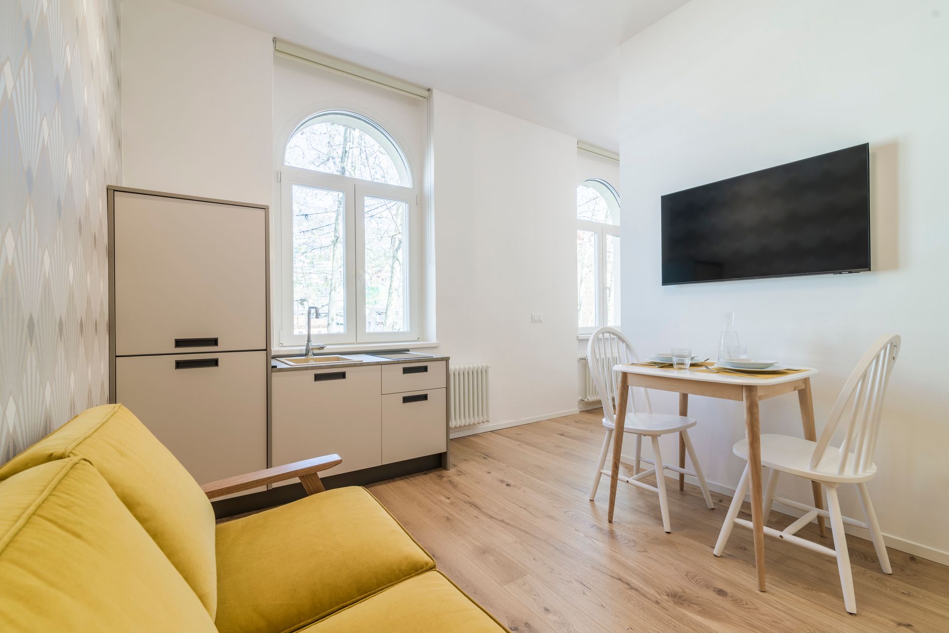 Ein Wohnzimmer mit einer gelben Couch, einem Tisch und Stühlen.
