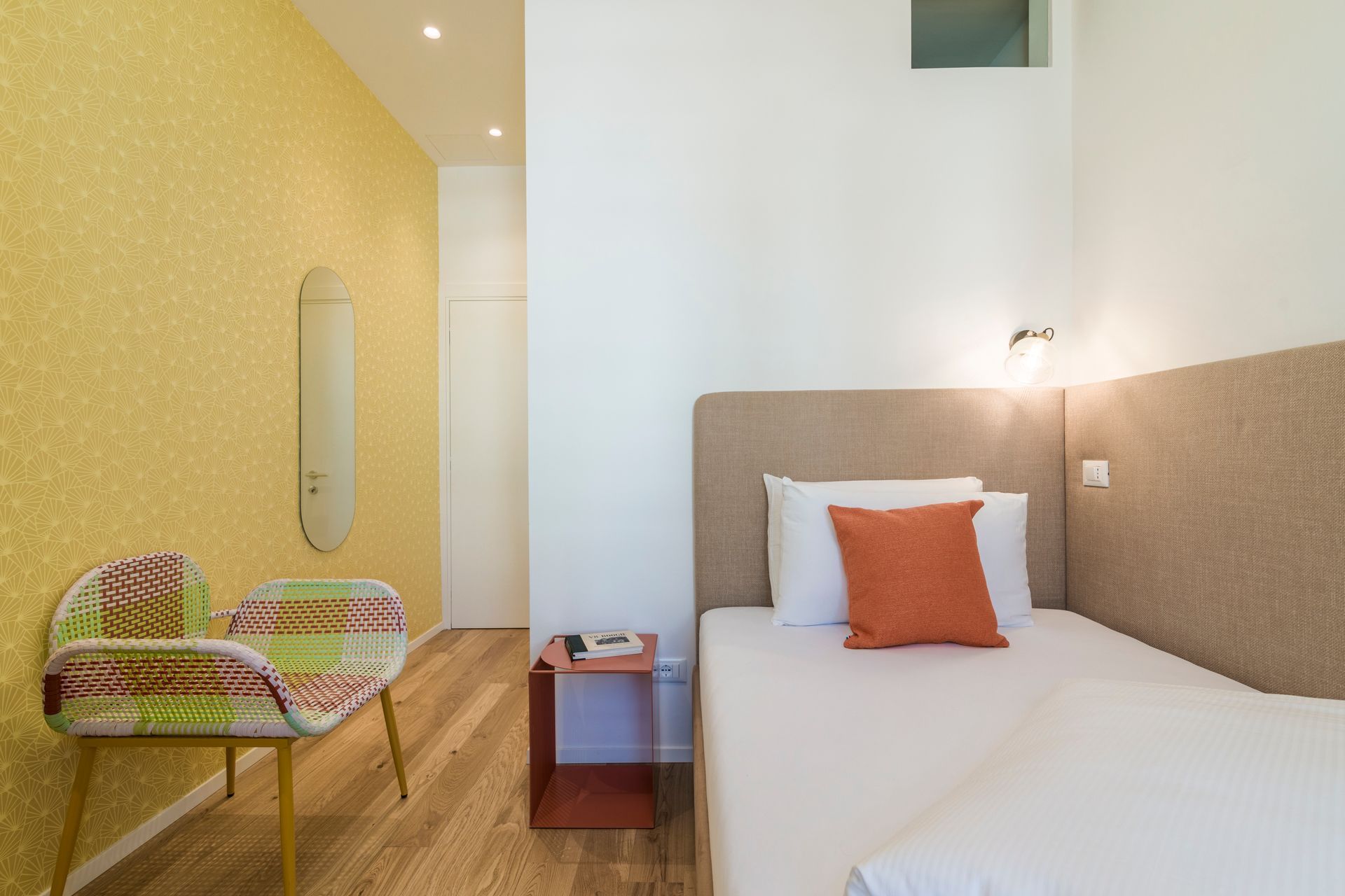 Ein Schlafzimmer mit einem Einzelbett, einem Stuhl und einem Spiegel.