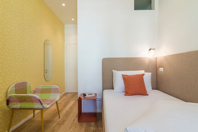 Una camera con un letto singolo e una sedia.