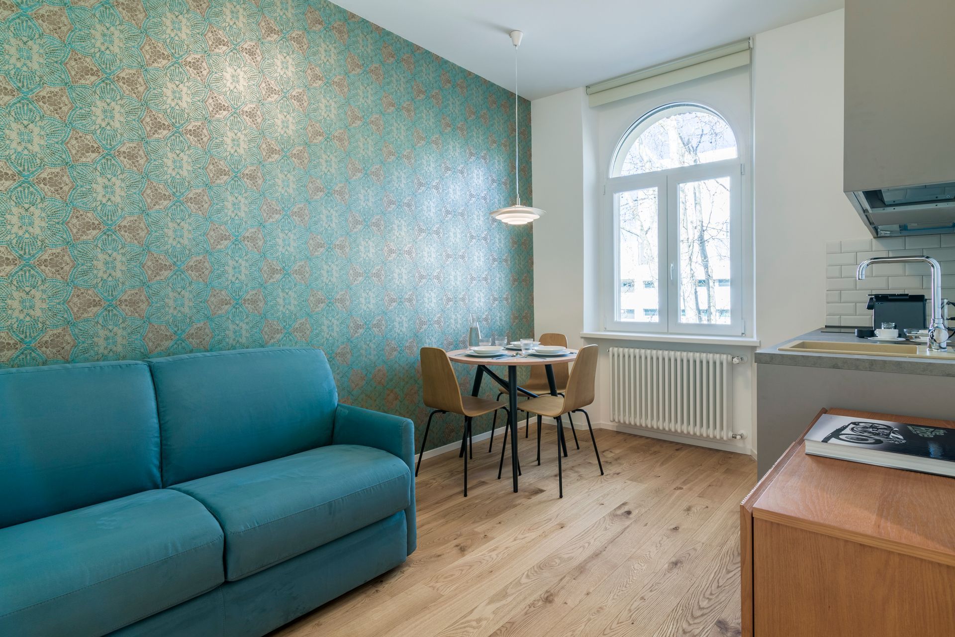 Ein Wohnzimmer mit einer blauen Couch, einem Tisch und Stühlen.