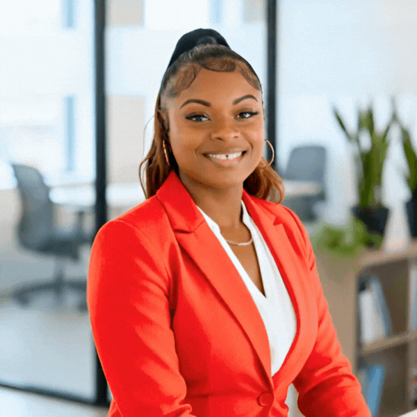 Woman in red blazer smiles in office. Phoenicia Glinn.