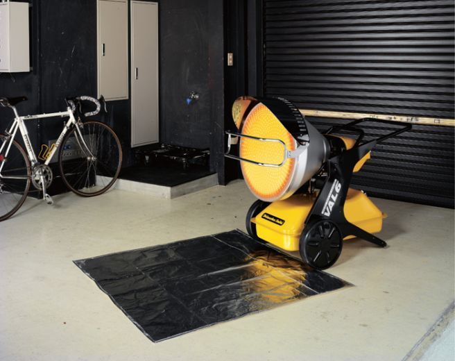 Garage with yellow heater on a reflective mat, a bicycle, and a closed garage door.