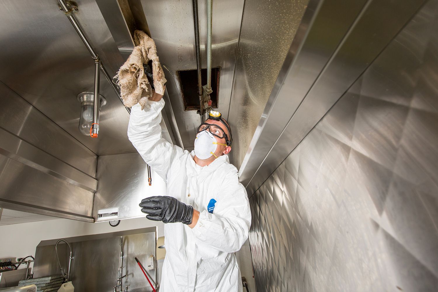 A professional cleaning a commercial kitchen exhaust system. A professional cleaning a commercial kitchen exhaust system.