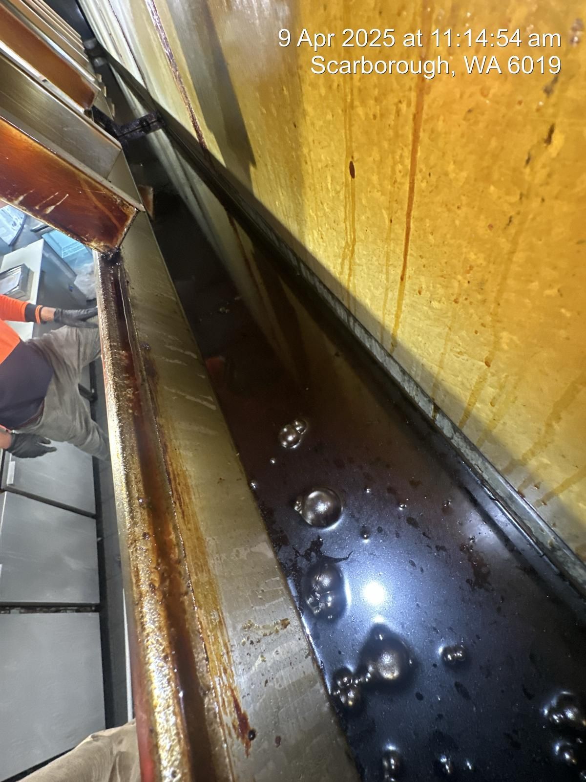 A person is working on a machine with a lot of oil on it.
